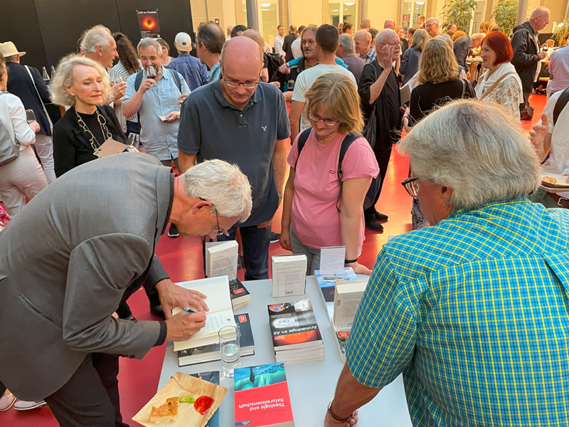 Heino Falcke signiert eines seiner Bücher "Licht im Dunkeln" nach seinem Vortrag an der Universität Bern am 20. Juni 2024
